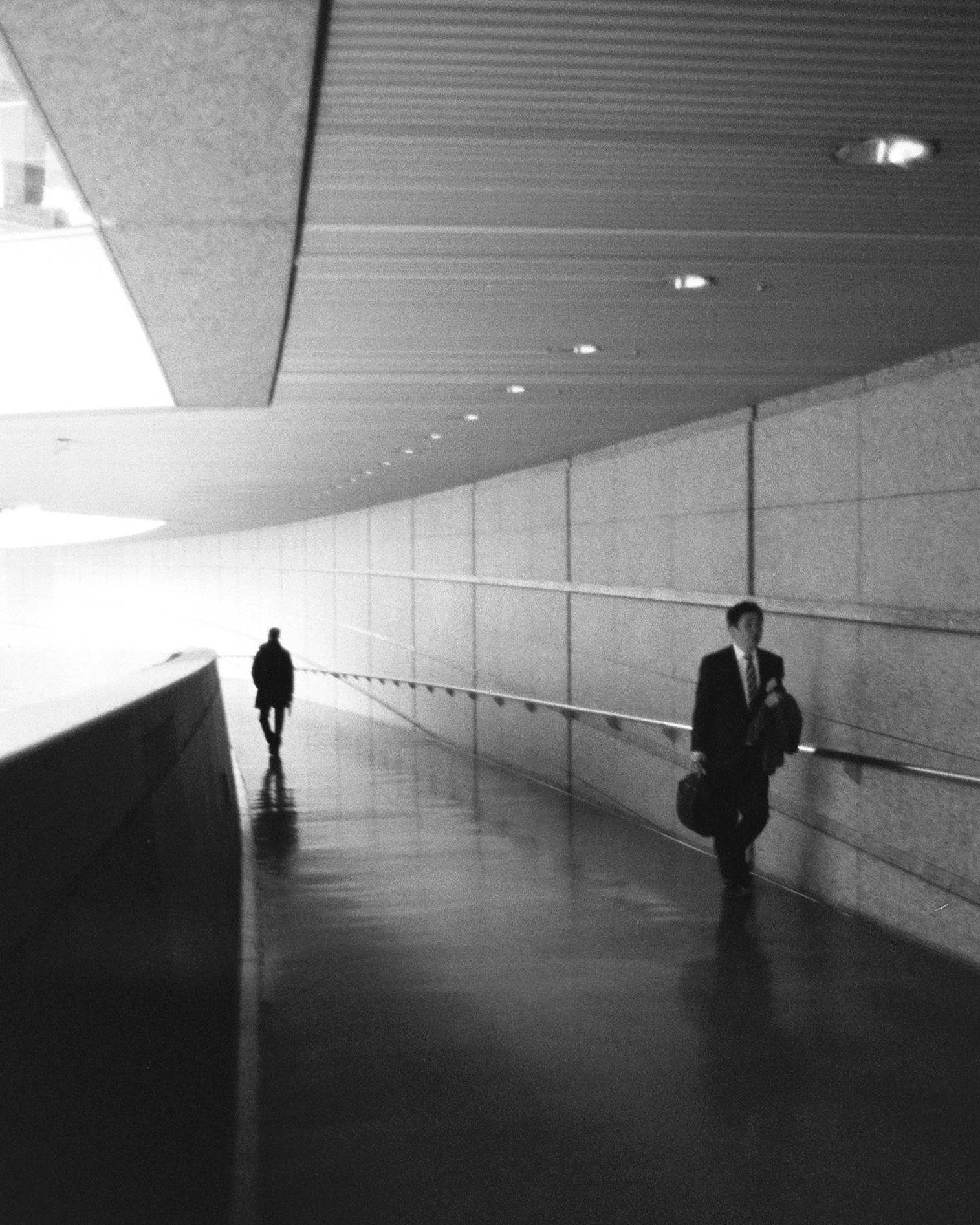 A person passing through a layered city scene, partly obscured by surface and shadow.