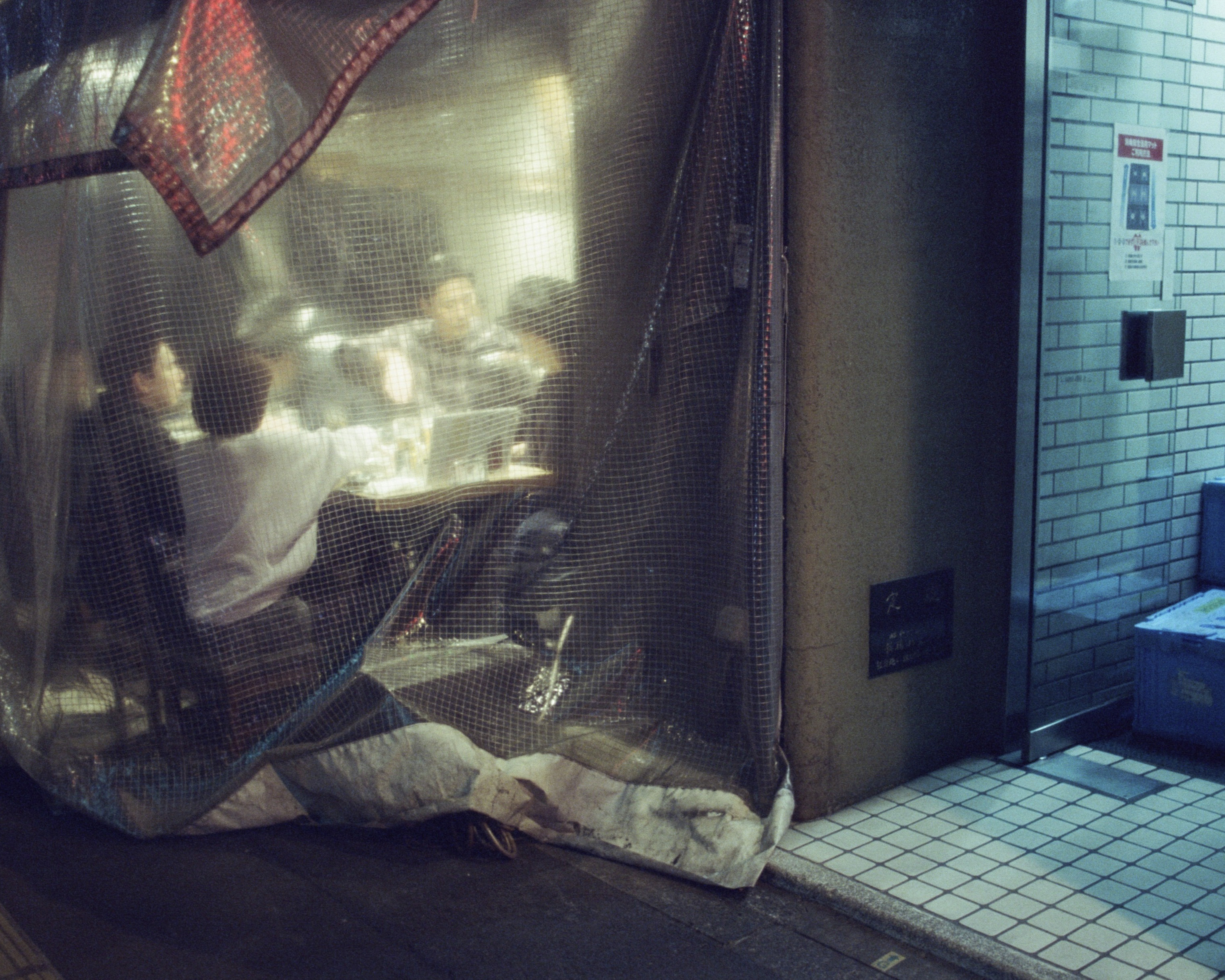 A Japanese street scene fragmented by reflections and window surfaces.